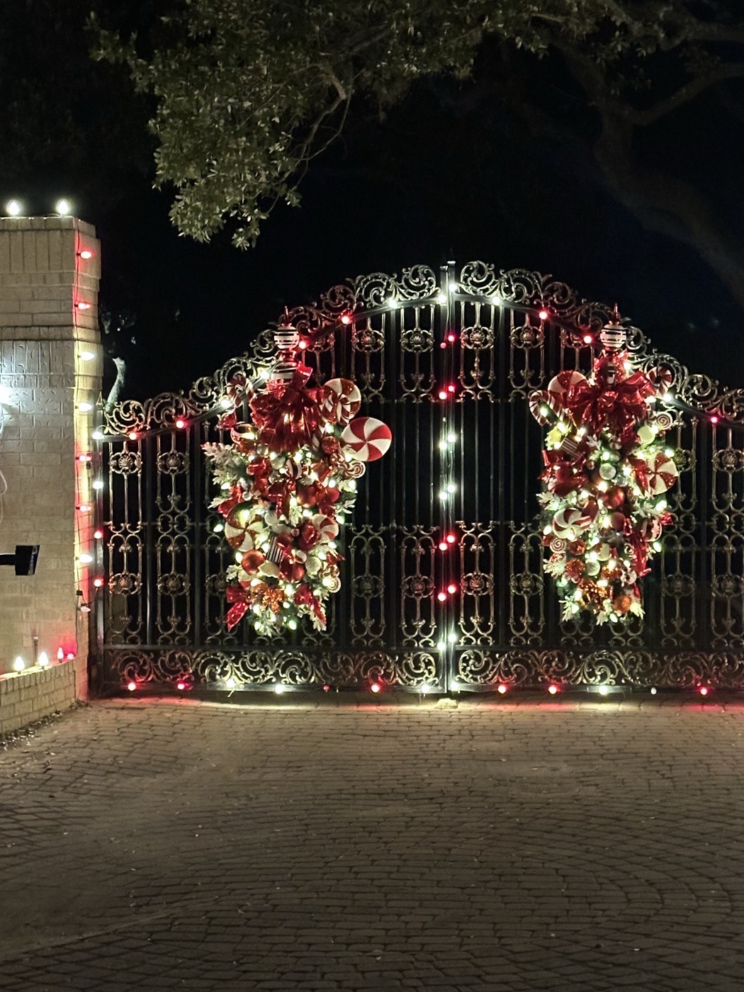 Ornate iron gate with lit red and white holiday swags