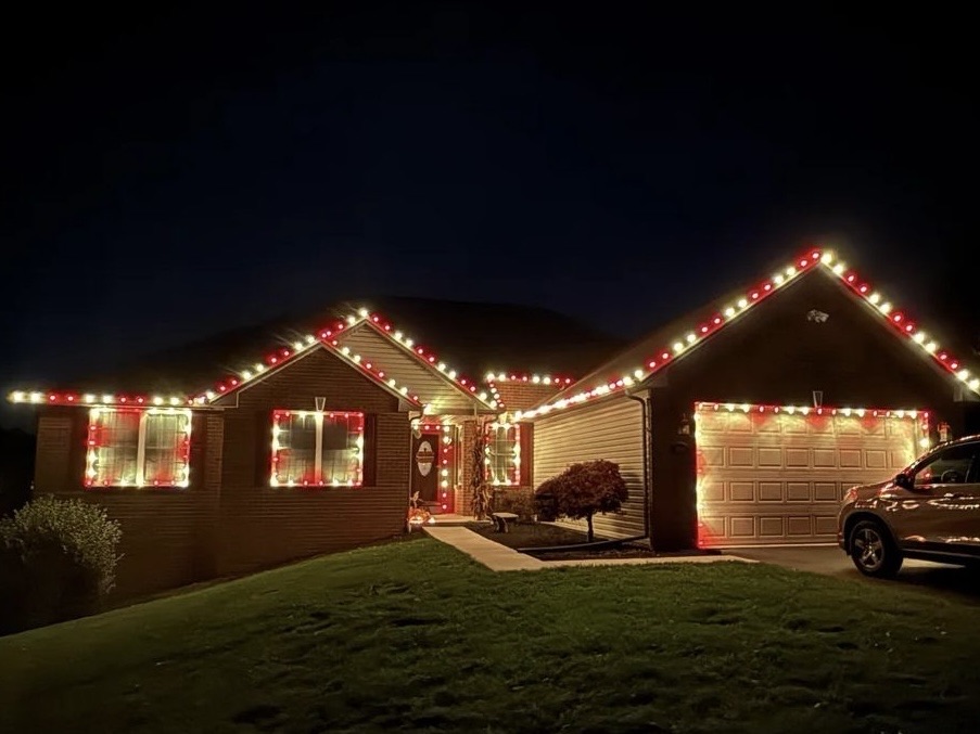 Roofline and garage of a home outlined in warm white Christmas lights